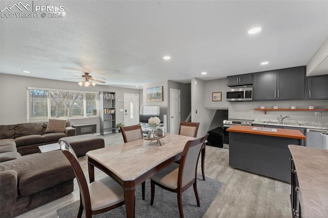 dining space featuring a textured ceiling, light hardwood / wood-style flooring, ceiling fan, and sink