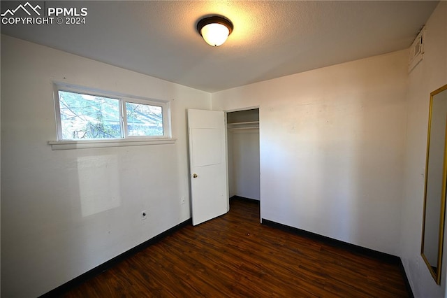 unfurnished bedroom featuring dark hardwood / wood-style flooring and a closet