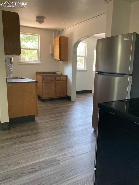 kitchen with light wood-type flooring, electric range, a healthy amount of sunlight, and sink