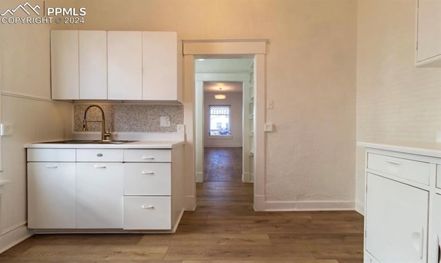 kitchen featuring sink, white cabinetry, backsplash, and light hardwood / wood-style flooring