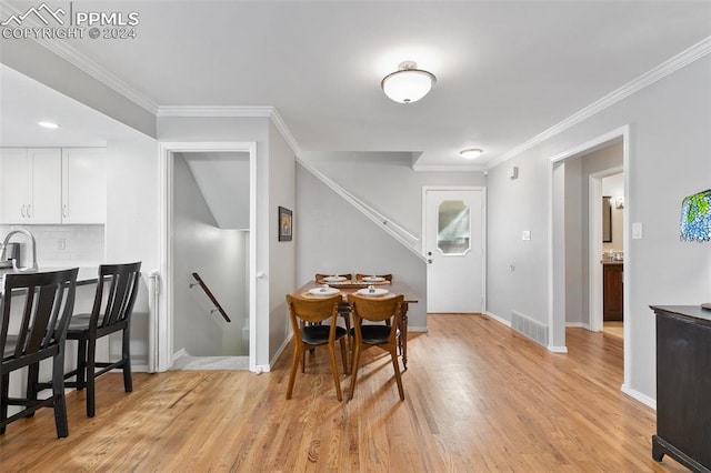 dining room with light hardwood / wood-style floors and ornamental molding