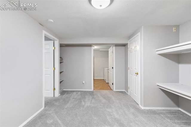 basement with a textured ceiling and light colored carpet