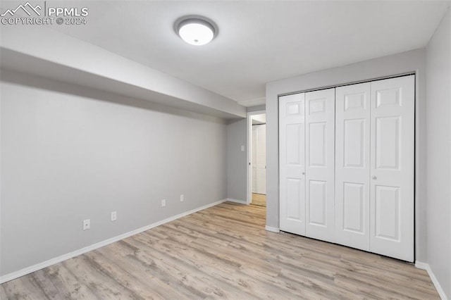 unfurnished bedroom with light hardwood / wood-style flooring and a closet