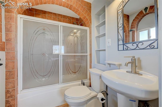 full bathroom with shower / bath combination with glass door, built in features, toilet, and sink