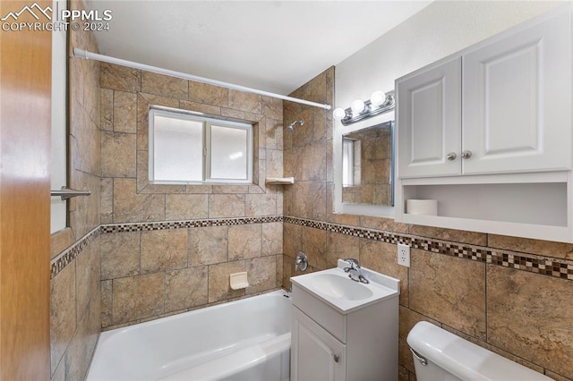 full bathroom with tiled shower / bath, vanity, tile walls, and toilet