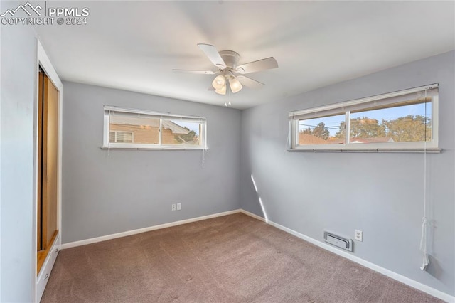 empty room featuring carpet flooring, ceiling fan, and a healthy amount of sunlight