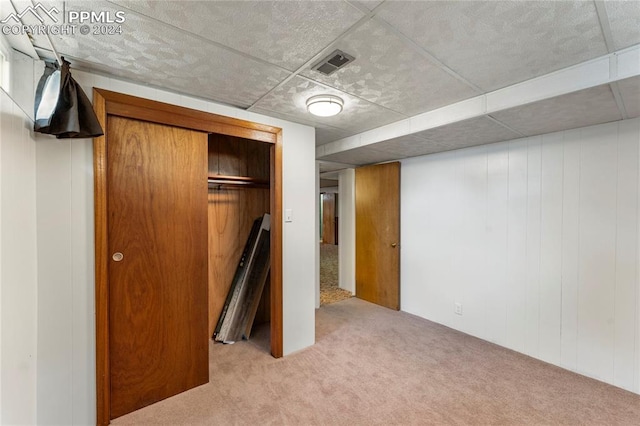 basement with wood walls and light carpet