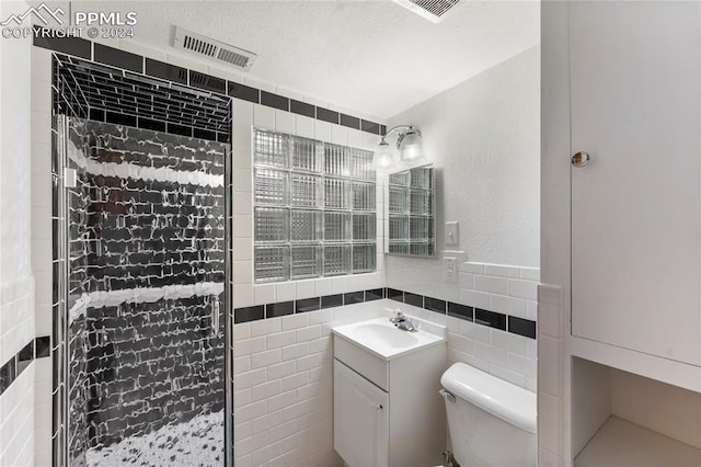 bathroom featuring vanity, toilet, tile walls, and a shower with shower door