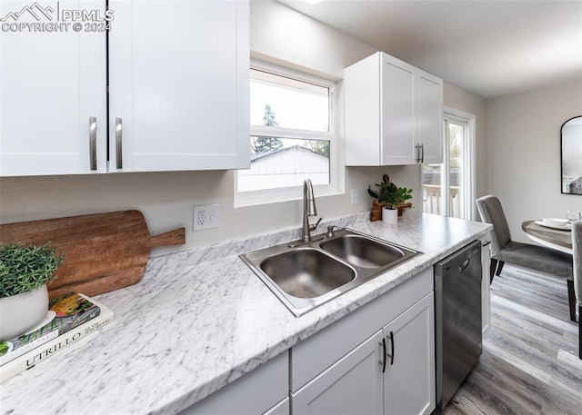 kitchen featuring dishwasher, hardwood / wood-style floors, sink, light stone countertops, and white cabinetry