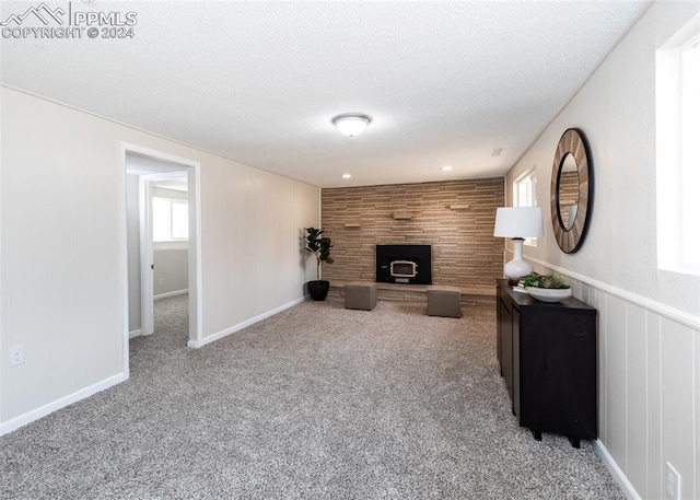 unfurnished living room featuring carpet floors, a textured ceiling, and wooden walls