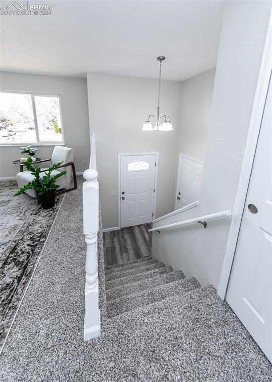 staircase with wood-type flooring and an inviting chandelier