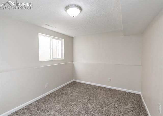 unfurnished room with a textured ceiling, vaulted ceiling, and carpet