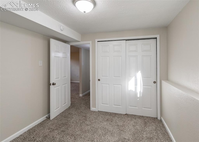 unfurnished bedroom featuring a closet, a textured ceiling, and light carpet