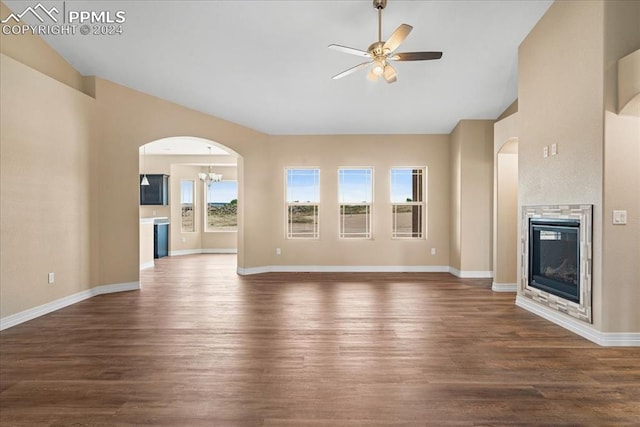 unfurnished living room with ceiling fan with notable chandelier and dark wood-type flooring