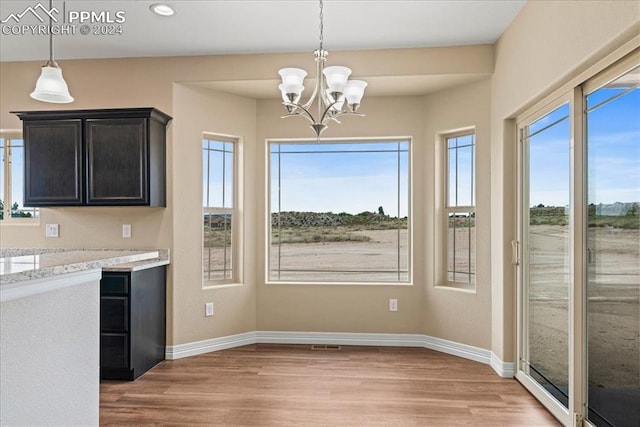 kitchen featuring an inviting chandelier, light stone countertops, decorative light fixtures, and light hardwood / wood-style floors