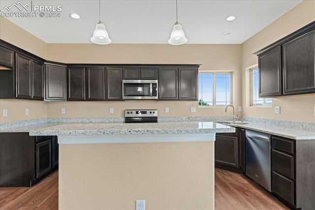 kitchen with appliances with stainless steel finishes, sink, light hardwood / wood-style floors, and hanging light fixtures