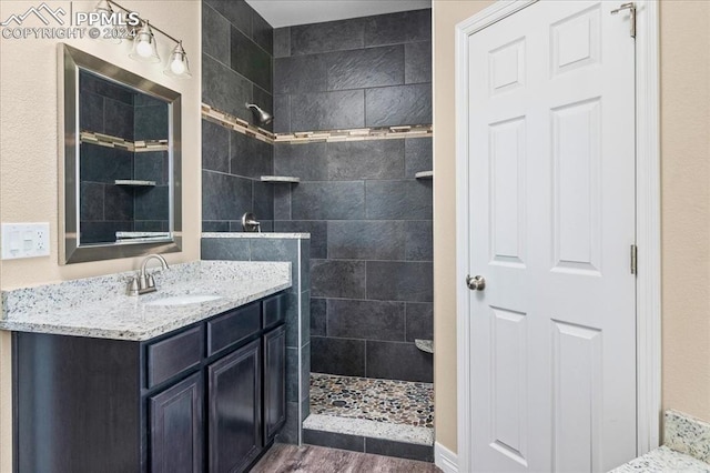 bathroom featuring vanity, wood-type flooring, and a tile shower