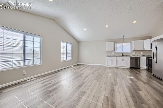 unfurnished living room with a textured ceiling, light wood-type flooring, lofted ceiling, and sink