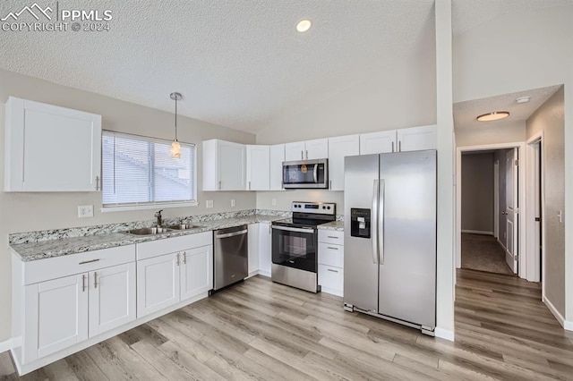 kitchen featuring stainless steel appliances, white cabinetry, sink, and decorative light fixtures