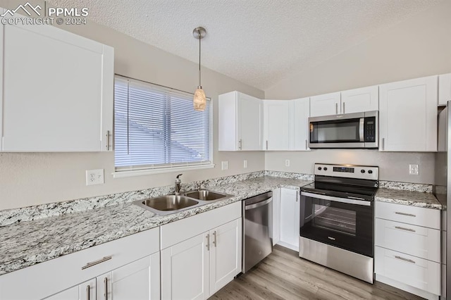 kitchen with stainless steel appliances, white cabinetry, sink, and lofted ceiling