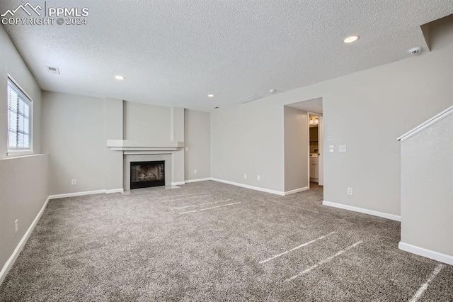 966 Daffodil St, Fountain, CO 80817 - unfurnished living room with a textured ceiling, carpet flooring, recessed lighting, a fireplace with flush hearth, and baseboards