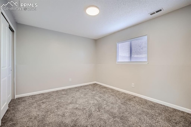 empty room featuring a textured ceiling and carpet