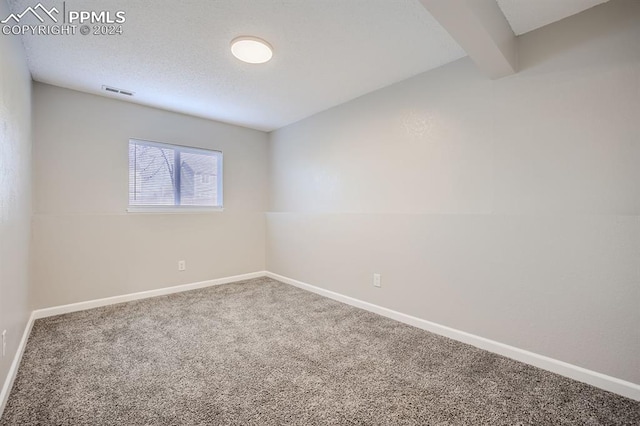 spare room with beamed ceiling and carpet flooring