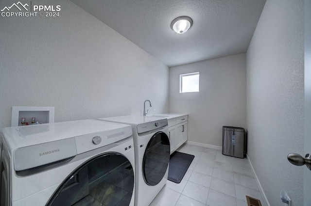 clothes washing area featuring cabinets, a textured ceiling, sink, light tile patterned floors, and washing machine and clothes dryer