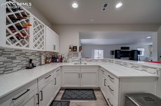 kitchen featuring white cabinets, kitchen peninsula, hardwood / wood-style floors, and tasteful backsplash