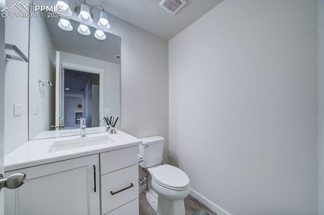 bathroom with toilet, vanity, and hardwood / wood-style flooring