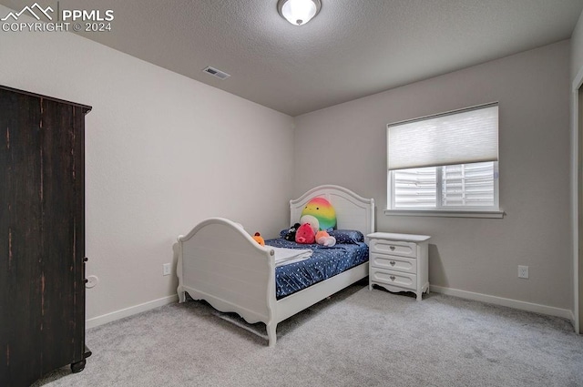 bedroom featuring a textured ceiling and light colored carpet