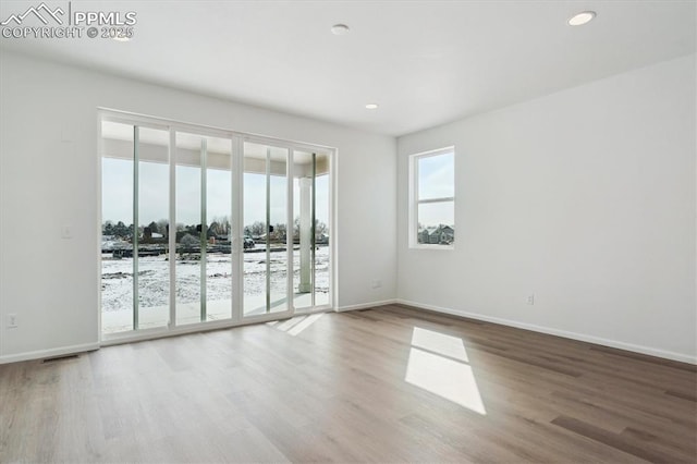 empty room with recessed lighting, wood finished floors, visible vents, and baseboards