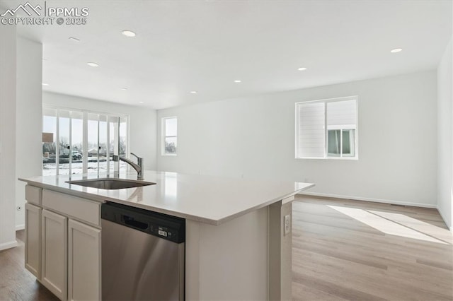 kitchen with a center island with sink, light countertops, dishwasher, and a sink