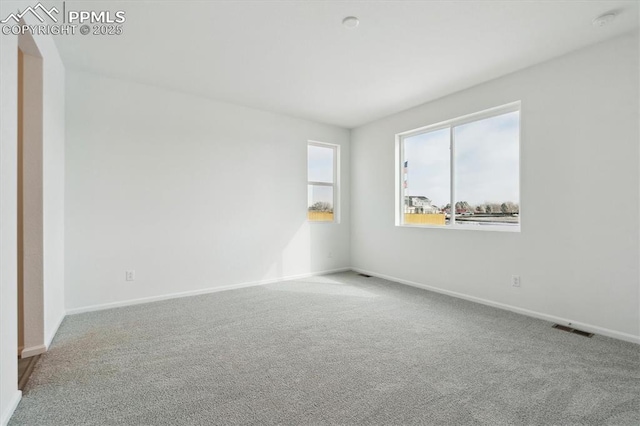 spare room featuring carpet flooring, visible vents, and baseboards