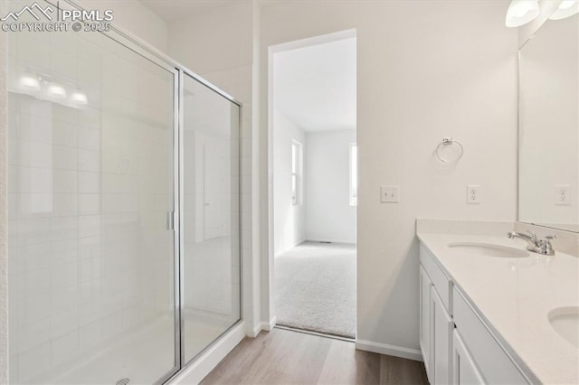 full bath featuring double vanity, wood finished floors, a stall shower, and a sink