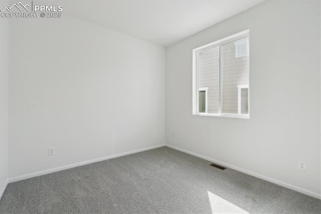 carpeted spare room featuring visible vents and baseboards