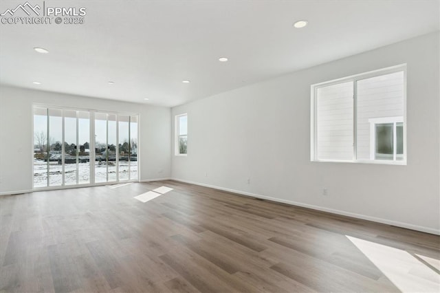 unfurnished room with baseboards, wood finished floors, and recessed lighting