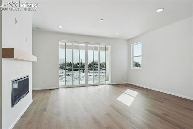 unfurnished living room with light wood finished floors, a glass covered fireplace, and recessed lighting