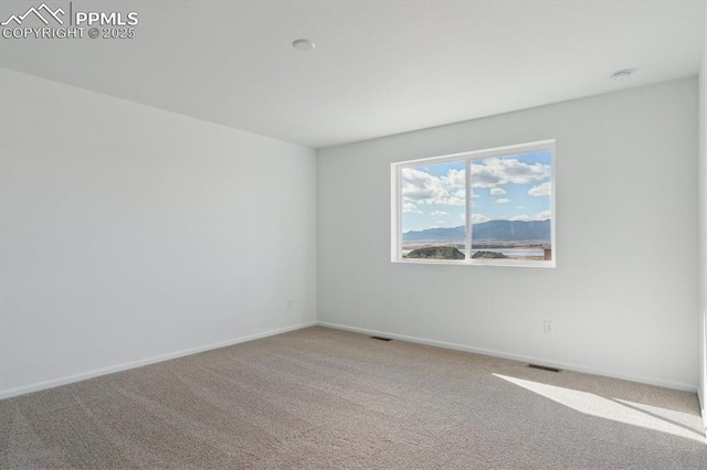 spare room featuring carpet flooring, baseboards, and visible vents