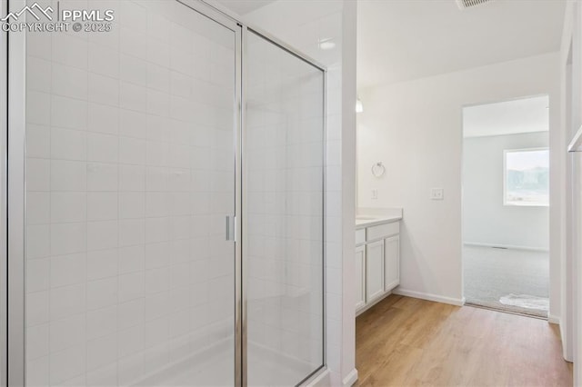 full bath featuring vanity, a shower stall, wood finished floors, and baseboards