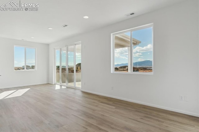 spare room with visible vents, plenty of natural light, and light wood-style floors