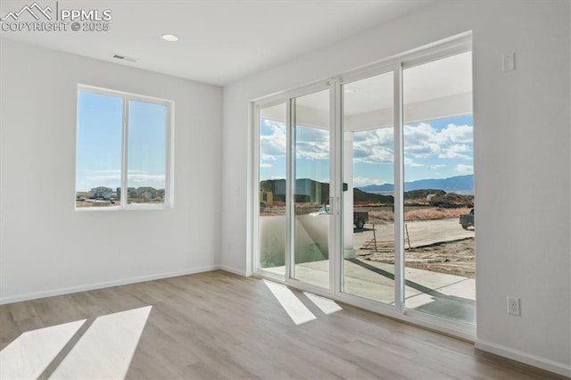 interior space with a mountain view, wood finished floors, visible vents, and baseboards