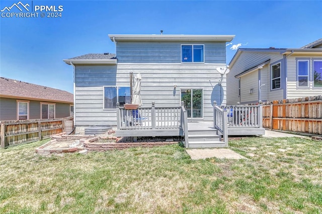 back of property featuring a wooden deck and a yard