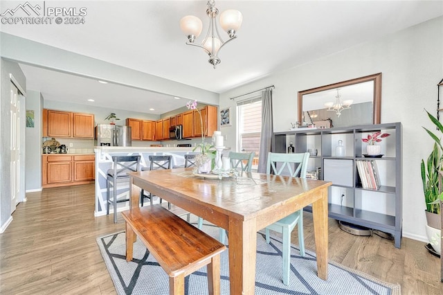 dining room featuring light wood-type flooring and an inviting chandelier