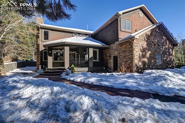 snow covered house featuring a porch