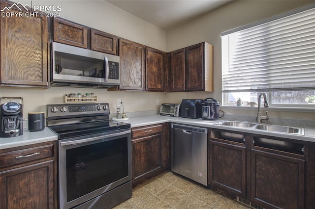 kitchen featuring appliances with stainless steel finishes, dark brown cabinets, and sink