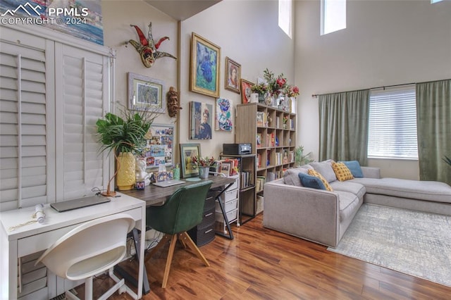 home office featuring a towering ceiling and hardwood / wood-style flooring