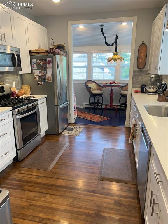 kitchen featuring decorative backsplash, dark hardwood / wood-style flooring, white cabinets, and stainless steel appliances