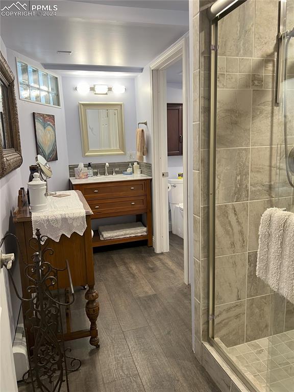 bathroom with wood-type flooring, vanity, and a shower with door