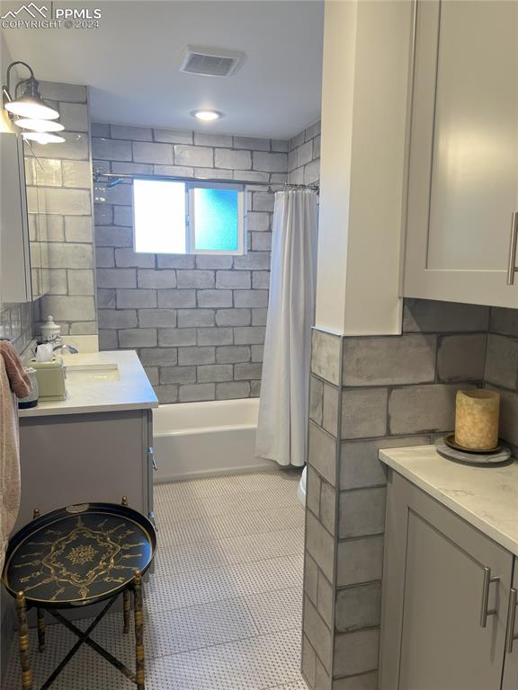 bathroom with vanity, tile patterned floors, tile walls, and shower / bath combo with shower curtain